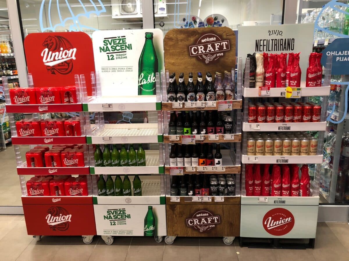 A display of liter beverages, including water and soda, is arranged on stacked Tosca Beverage Trays in a grocery store aisle.
